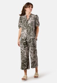 Green and white patterned two-piece outfit featuring a short-sleeve button-up top and wide-leg pants, made of a lightweight fabric.