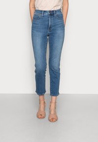 Höga blå denimjeans med slim fit, kort längd och rå nederkant. Matchat med tanfärgade sandaler med remmar.