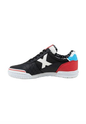 Zapatilla negra de caña baja con suela blanca, logo X blanco, talón rojo, lengüeta azul en el talón y textura acolchada en la puntera y los laterales.