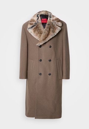 Brown double-breasted coat with black buttons and large faux fur collar. Features side pockets and a straight-cut design. Brand tag visible inside.