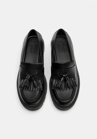Schwarze Lederloafers mit runder Spitze, dekorativem Quastenakzent und genähten Details auf dem Obermaterial sowie Gummisohle.
