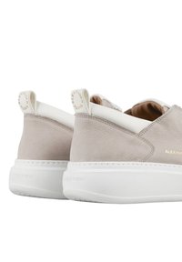 Sneakers in pelle grigio chiaro con suole in gomma bianca, caratterizzati da un design minimalista e un logo impressa sul tallone e sulla linguetta.
