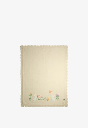 Kremfarvet tæppe med broderede kaniner, blomster og en sommerfugl langs den ene kant med bølget kant.