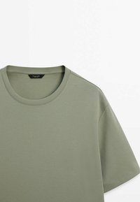 T-shirt en coton vert olive avec un col rond et des manches courtes ; texture lisse ; possède une étiquette avec le nom de la marque à l'intérieur.