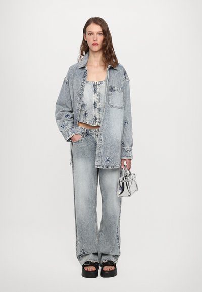 Light blue denim outfit featuring a cropped top and oversized jacket. Silver hardware accents and a metallic handbag complete the look.