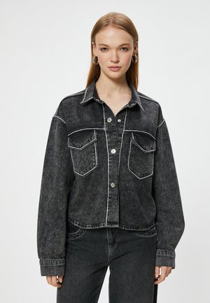 Sort denimjakke med en cropped design, kontrasterende hvid syning, to brystlommer og knaplukning; har en krave og en afslappet pasform.
