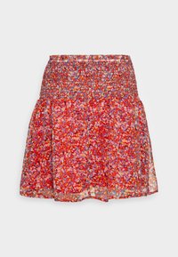 Jupe fleurie rouge avec une taille smockée, présentant une couche de tissu transparent. Les motifs comprennent de petites fleurs dans des tons de rose, orange et violet.