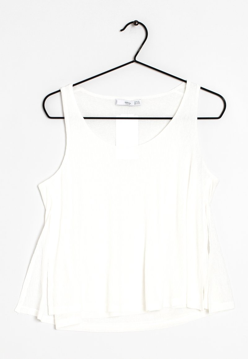 Haut blanc sans manches ample suspendu sur un cintre métallique noir sur fond blanc.