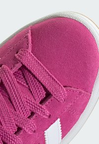 Roze antilop tenisice s teksturiranim vezicama i bijelim bočnim prugama. Imaju gumeni potplat i detaljno šivanje duž rubova.