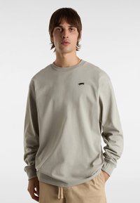 Lichtgrijze langemouwen T-shirt van zachte katoen met een ronde hals. Met een klein zwart logo op de borst. Regular fit.