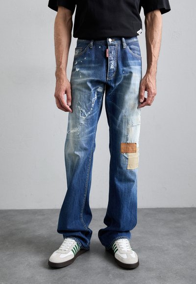 Denim farkut, jotka ovat kuluneet siniset, rento istuvuus, jossa on beigeä ja ruskeaa kangasta sekä näkyviä reikiä tekstuurin muuttamiseksi.