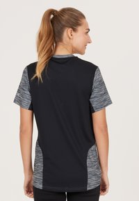 Svart träningströja med grå mönstrade kortärmar och sidopaneler. Har en rund halsringning och ett texturerat tyg.