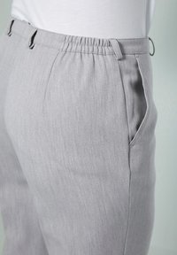 Pantaloni grigi chiari con un tessuto testurizzato, vita elasticizzata, tasche laterali e passanti per cintura, che mostrano una vestibilità su misura e un design casual.