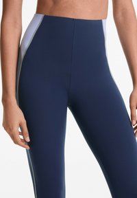 Leggings s visokim strukom u mornarsko plavoj boji s elegantnim panelima u kontrastnim bojama, glatke teksture tkanine i suptilnim šavovima duž šavova.