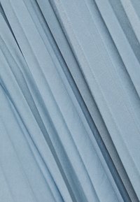 Hellblauer plissierter Stoff mit glatter, weicher Textur, der vertikale Linien und verschiedene Schattierungen aufweist und eine geschichtete Optik erzeugt.