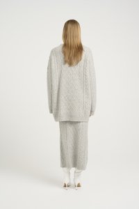 Set din două piese de culoare gri deschis, tricotat, cu un design cu fire încrucișate. Puloverul oversized și fusta lungă au margini ribbate și un finisaj texturat.