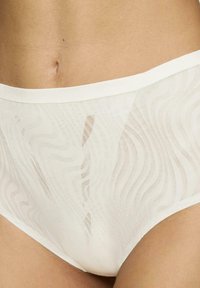 Panties blancas de cintura alta que presentan una tela transparente y texturizada con patrones ondulados y una cinturilla suave.