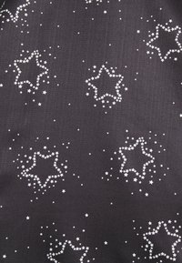 Tissu sombre orné de grappes de petites étoiles blanches formant des formes d'étoiles plus grandes dispersées sur la surface.