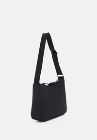 Borsa a spalla nera in tessuto con una texture liscia. Presenta una tracolla regolabile e un'apertura con zip sulla parte superiore per l'accesso.