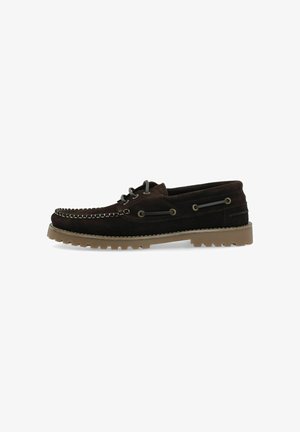 Chaussure bateau en daim brun foncé avec semelle en caoutchouc beige et détail lacé sur les côtés, vue de profil gauche.