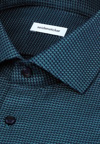 Dunkeltealfarbenes Hemd mit einem strukturierten, gewebten Muster. Es verfügt über einen Kragen und einen einzelnen Knopf, gekennzeichnet mit einem weißen "seidensticker"-Etikett.