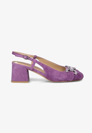 Scarpa slingback in suede viola con tacco a blocco, caratterizzata da un accento decorativo di un fiocco metallico sulla punta e una tracolla regolabile.