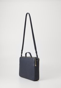 Borsa in pelle blu navy con una forma rettangolare strutturata, zip dorata, manico superiore e tracolla regolabile. Texture liscia.