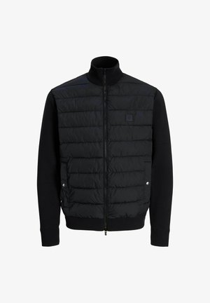 Giubbotto a forma di piumino nero con chiusura a zip, caratterizzato da una parte superiore imbottita e maniche e orlo inferiori in maglia. Include un alto colletto e un branding discreto.