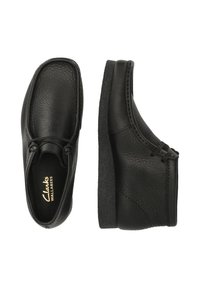 Svarta läderskor med en strukturerad yta, rund tå och snörningsdesign. Tjock gummisula med en lätt klack, med Clarks-logotypen inuti.