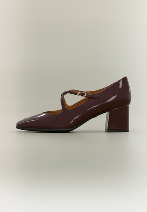 Chaussure Mary Jane en cuir verni marron foncé avec petit talon bloc et bride à boucle, vue de profil sur un fond uni.