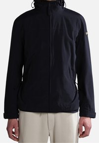 Chaqueta de color azul marino con cremallera frontal, capucha ajustable, puños elásticos y bolsillos laterales. Fabricada con un material ligero y resistente al agua.