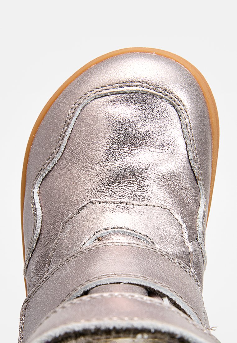 Stivale alla caviglia metallico argento con una texture liscia, cinturino in velcro, punta arrotondata e suola in gomma marrone chiaro.