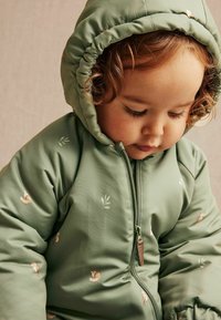 Groene gewatteerde jas met een capuchon, voorzien van kleine dieren- en bladprints. Ritsluiting met een leren trekker aan de voorkant.