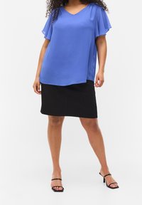 Blouse bleu léger à col en V avec des manches volantes, associé à une jupe noire jusqu'aux genoux et des sandales noires à lanières. Design épuré, sans motifs.