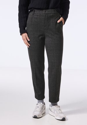Grijze geruite broek met een getailleerde pasvorm, voorzien van zijzakken en een enkele knoopsluiting, gecombineerd met witte en grijze sneakers.