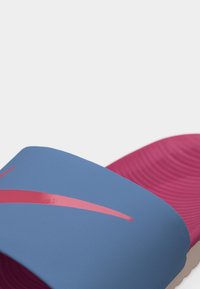 Μπλε λουράκι σανδαλιού slide με κόκκινο λογότυπο Nike swoosh και ροζ υφασμένο πέλμα.