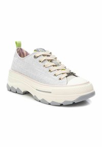 Zapatilla de color gris claro con parte superior de tela texturizada, plataforma moderada y suela de goma blanca en contraste, con cordones beige y un talón verde.