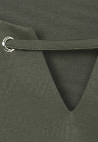 Olijfgroen top met een v-hals ontwerp, voorzien van zilverkleurige hardware en een geweven textuur. Strikken zijn door metalen ringen gehaald.