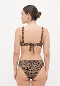 Bikini à imprimé léopard avec un dos noué, des bretelles réglables, un tissu doux et une coupe haute flatteuse.