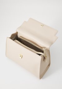 Beige syntetisk lærveske med strukturelt design, med en dekorativ klaff i gulltone og to indvendige glidelåslommer.