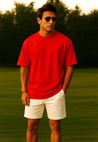 T-shirt rossa in cotone con maniche corte abbinata a pantaloni corti bianchi. L'individuo indossa occhiali da sole e ha un tatuaggio visibile sul braccio sinistro.