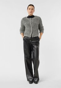 Szary kardigan o fakturowanej strukturze z okrągłym dekoltem, zapinany na guziki, z rękawami do połowy przedramienia, zestawiony z czarnymi skórzanymi spodniami o szerokich nogawkach.