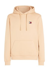 Beige hoodie gemaakt van stof met een zachte textuur. Voorzien van een buidelzak en een logo-patch op de linkerkant van de borst. Verstelbare koorden.