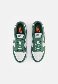 Nike sportcipők zöld bőr felsőrésszel, fehér szintetikus orr résszel, zöld fűzőkkel és narancssárga logóval a sötétzöld nyelvén. Lyukacsos orr részlet.