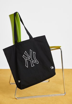 Sac en toile noir avec logo des New York Yankees brodé en blanc. Fabriqué en tissu, il dispose de deux anses noires et d'une petite étiquette MLB sur le côté.