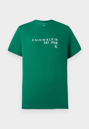 Grøn T-shirt med korte ærmer med hvid "Calvin Klein EST. 1968" og lille "cK" logo trykt på brystet.
