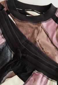 Multicolored top featuring abstract patterns in pink, brown, and black hues. Black elastic neckline with "time to dream" text; soft texture.