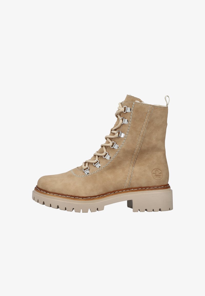 Botín de tobillo de ante beige con herrajes plateados, cordones y costuras blancas en contraste. Presenta una suela de goma gruesa beige.