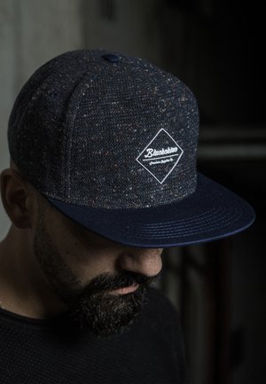 Dark blue snapback cap made of textured fabric, featuring a white diamond patch with "Blacksters" logo and a flat brim.