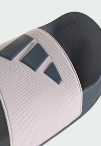 Czarno-różowe klapki z teksturowanym paskiem, na którym znajduje się ciemne logo. Podeszwa jest gładka, nieco podwyższona i charakteryzuje się trwałą konstrukcją.